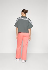 Gray cropped T-shirt with white stripes on the shoulders, paired with coral wide-leg pants, viewed from the back, featuring a relaxed fit.