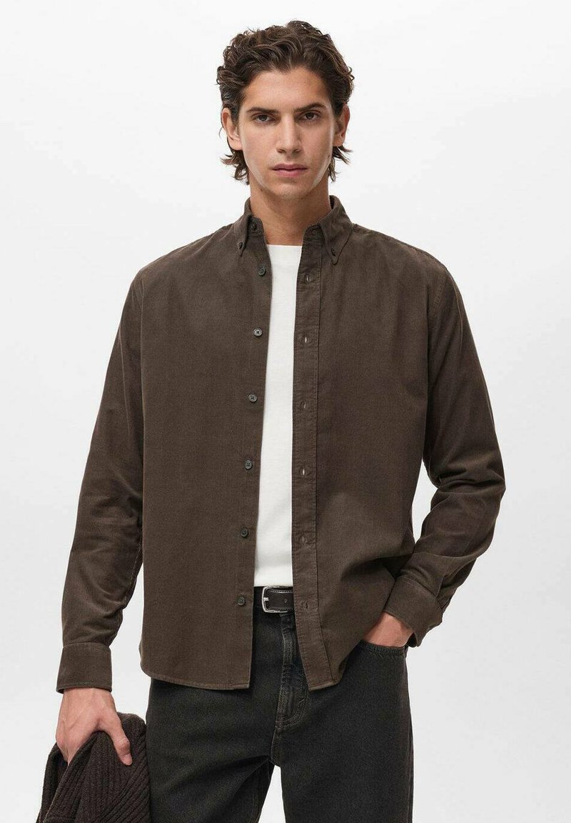 Camisa marrón de botones hecha de una tela suave, con cuello y placket frontal con botones, combinada con una camisa blanca por debajo.