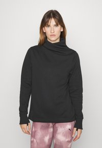 Fekete, hosszú ujjú pulóver, galléros nyakkal és bordázott mandzsettával, világos rózsaszín mintás leggings-szel párosítva. Sima szövet textúra.