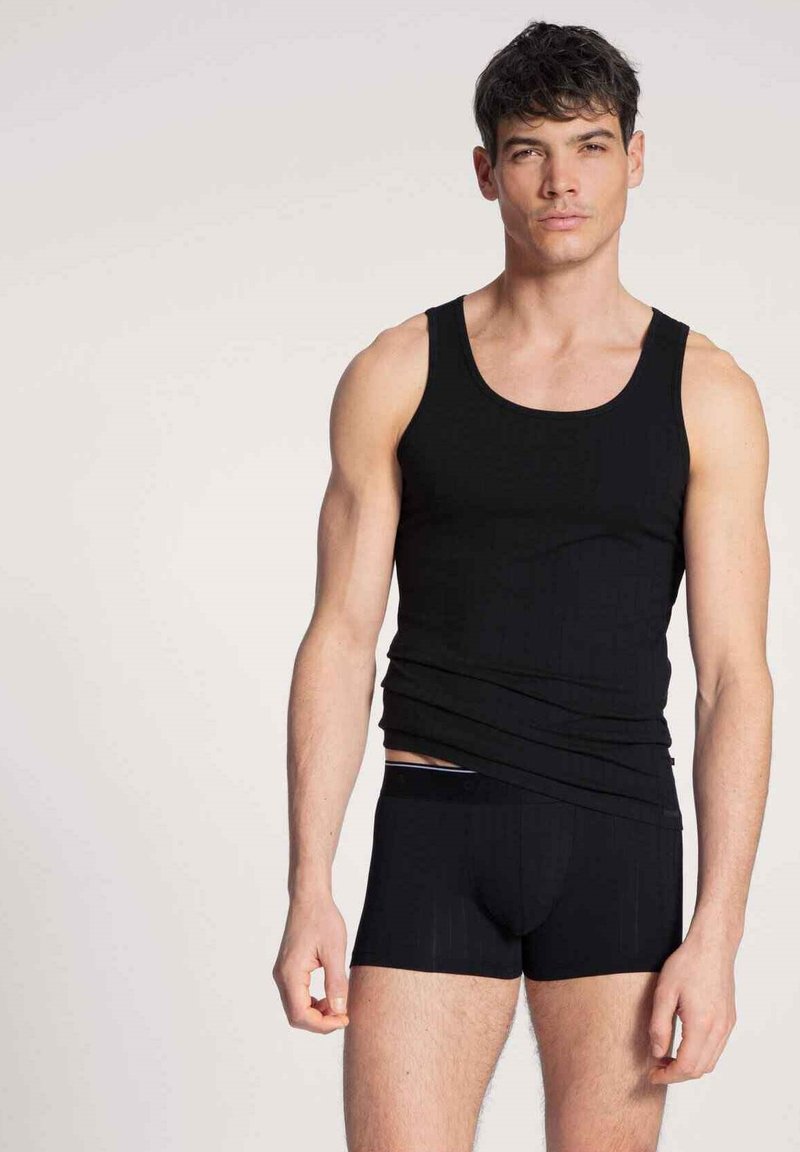 Zwarte tanktop en onderbroek van gladde stof. De tanktop heeft brede schouderbanden en een aangesloten ontwerp. De onderbroek heeft een subtiel gestreept patroon.