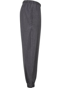 Pantalons de jogging gris, fuselés, avec une taille élastique et des poignets élastiques, présentant une texture lisse et des poches latérales.