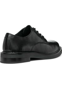 Chaussure oxford en cuir noir avec un bout arrondi, un laçage, une texture lisse et un talon bas empilé. Couture détaillée autour de la semelle.