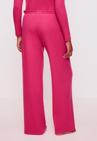 Roze, wijde broekspijpen gemaakt van zacht, gestructureerd materiaal. Kenmerkt zich door een gladde tailleband en een casual, ontspannen pasvorm.