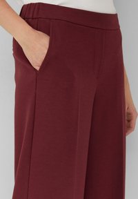 Bordeaux wijde broek van textuurstof, met zijzakken en een elastische tailleband voor comfort.