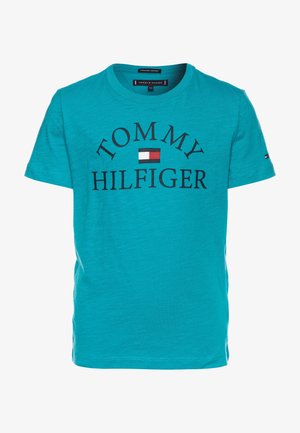 Camiseta turquesa de algodón orgánico, con cuello redondo, que presenta "TOMMY HILFIGER" en texto negro en negrita y un pequeño logo de bandera en el centro.