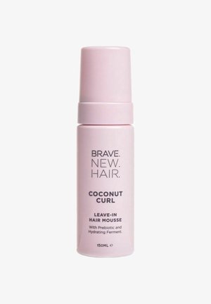 Pink cylindrisk flaske med leave-in hårmousse og hvid tekst. Etiketten siger "Coconut Curl" med præbiotikum og fugtgivende ferment. Indeholder 150 ml.