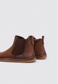 Brown leather ankle boots with elastic inserts, rounded toes, textured finishes, and pull tabs at the back, set on flexible rubber soles.