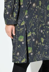 Blumenmuster-Tunika in Dunkelblau mit grünen und beigen Pflanzenmotiven. Mit langen Ärmeln und einem seitlichen Schlitz. Glatte Textur, leichtes Material.