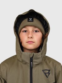 Giovane che indossa una giacca a vento verde oliva con cappuccio e zip nera, abbinata a un berretto a coste con logo, espressione neutra, sfondo chiaro.