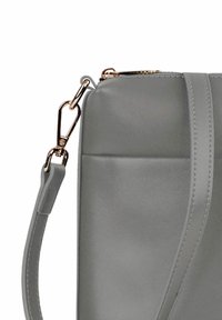 Šedá kožená kabelka s hladkým povrchem, s tenkým popruhem a zlatými detaily na zipovém uzávěru.