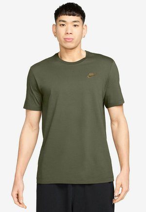 Camiseta Nike de color verde oliva con cuello redondo, mangas cortas y un pequeño logotipo dorado en el lado izquierdo del pecho. Tela suave, corte relajado.
