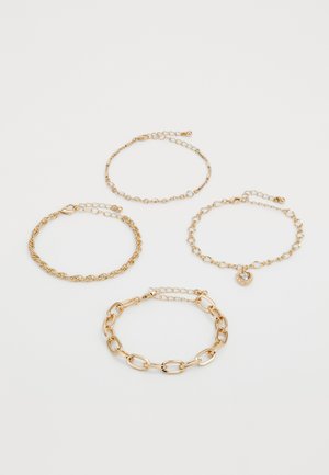 Vier delicate gouden schakelarmbanden met verschillende schakelstijlen, waarvan er één een hartvormige bedel met een heldere steen bevat.