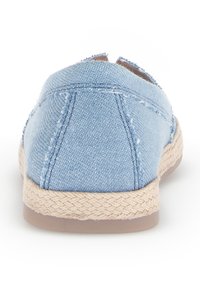 Zapato slip-on de denim azul claro con suela de yute trenzado, que presenta una puntera redonda y detalles de costura, creando un diseño casual y texturizado.