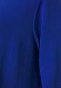 Mjuk ullblandningströja i klar koboltblå, med en slät textur, figurnära ärmar och en sömlös design med minimal detaljering.