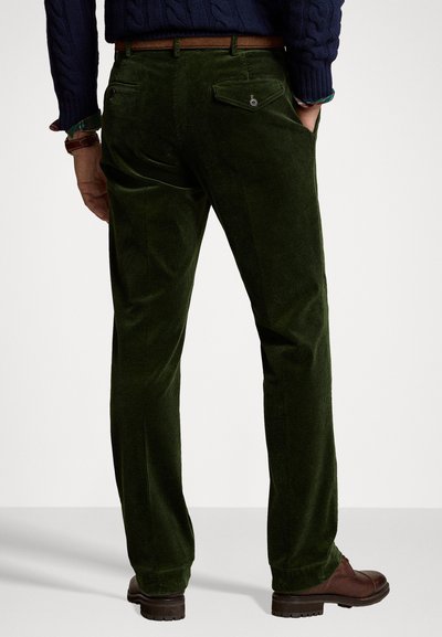 Grønne kordfløjl bukser med lige pasform, som har to baglommer og en glat tekstur. Båret med mørkebrune sko og et lysebrunt bælte.