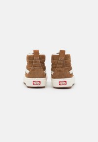 Brune semskede høye sko med hvite detaljer, polstret krage og gummisåle. Har en pull tab og Vans-logo bak.