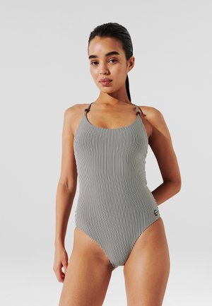 Costume intero a righe bianco e nero con scollo a goccia, spalline sottili e dettaglio logo laterale, realizzato in materiale liscio e elastico.