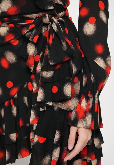 Μαύρο ύφασμ�α με κόκκινες και μπεζ πουά βούλες· διαθέτει στρωματοποιημένα βολάν και διακοσμητική ζώνη δεμένη με κόμπο. Μαλακή υφή και ρέουσα σχεδίαση.