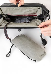 Borsa in pelle nera con rivestimento in tessuto a righe, dotata di un compartimento con zip. Un piccolo sacchetto coordinato è attaccato con un moschettone.