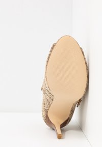 Sandaalit korkean korolla, vaalean beigen sävyinen, jossa on kauniisti kuvioitu päällinen, terävä kärki ja sileä, vaalea pohja, jossa on brändin painatus ja stiletto-korko.