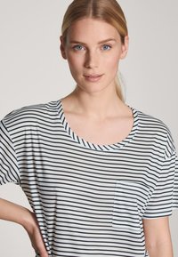 Gestreept t-shirt met een ronde hals, korte mouwen en een voorkantzak. De stof heeft horizontale zwart-witte strepen.