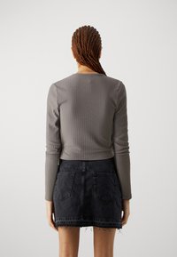 Gray ribbed long-sleeve top with fitted design, paired with a black denim mini skirt featuring frayed hem and two back pockets.