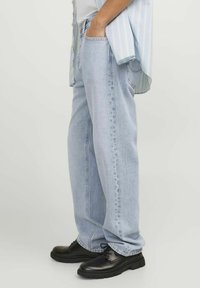 Lichtblauwe denim jeans met een ontspannen pasvorm, voorzien van gestikte zakken en een rechte pijp, gecombineerd met zwarte veterschoenen.