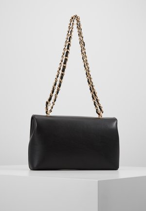 Zwarte rechthoekige handtas met gewatteerde gouden kettingriem, gepresenteerd op een wit oppervlak tegen een effen achtergrond.