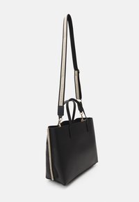 Borsa a tracolla nera in pelle con doppi manici superiori, tracolla regolabile e un accento laterale color crema. Caratterizzata da hardware in tonalità oro.