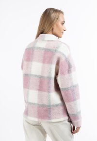 Lyserød og hvidternet fleece-skjortejakke med grå accenter, der har klassisk krave og afslappet pasform. Blød tekstur og hyggelig design.