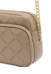 Bolso bandolera de piel sintética beige con patrón de logotipos en relieve, dos compartimentos con cremallera y una correa de cadena en tono dorado.