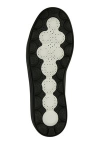 Svart och vit skosula med cirkulära mönster. Den översta halvan är vit med perforeringar, medan den nedre halvan är svart med texturerade cirklar.