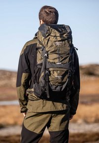 Olijfgroene rugzak met zwarte accenten, 70L capaciteit, meerdere compartimenten, verstelbare schouderbanden en een bovenste trekkoordsluiting.