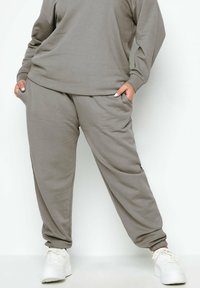 Grijze katoenmix sweatpants met elastische boorden en zijzakken, gecombineerd met een bijpassende sweatshirt, en gedragen met witte sneakers.