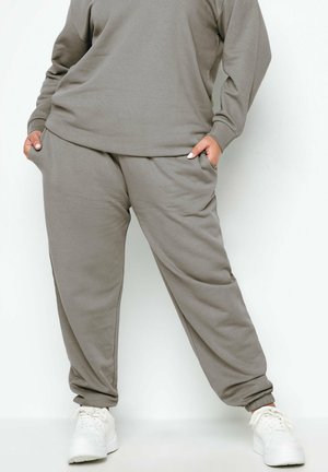 Graue Sweatpants aus Baumwollmischung mit elastischen Bündchen und Seitentaschen, kombiniert mit einem passenden Sweatshirt und getragen mit weißen Turnschuhen.