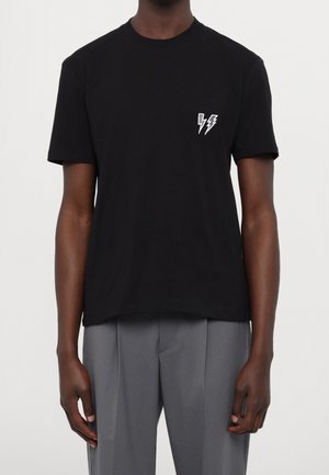 Czarna bawełniana koszulka z okrągłym dekoltem, z białym graficznym wzorem błyskawicy na lewej piersi i krótkimi rękawami.