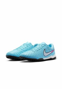 Light blue synthetic soccer cleats with textured upper, black rubber outsole, and a white Nike swoosh accented by a pink stripe.