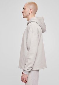 Lys grå oversized hoodie lavet af bomuldsblanding. Har en front kangaroo lomme, ribbede manchetter og hætte med snøre. Blød tekstur.