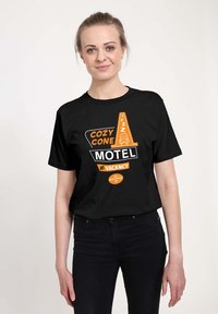 Czarna koszulka z nadrukiem w pomarańczowym i białym kolorze, z napisem "COZY CONE MOTEL" oraz "BRAK WOLNYCH MIEJSC", w luźnym kroju.