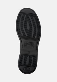 Black rubber shoe sole with textured grip, "CAMPER" logo centered, size 42, and additional markings near the heel area.