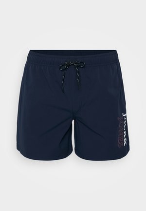 Navy blue swim shorts made of lightweight fabric, featuring an elastic waistband with a drawstring and a logo detail on the left side.