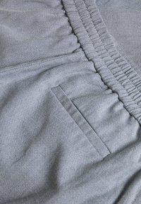 Grå tygshorts med en strukturerad väv, elastisk midja och en liten infälld ficka på sidan.