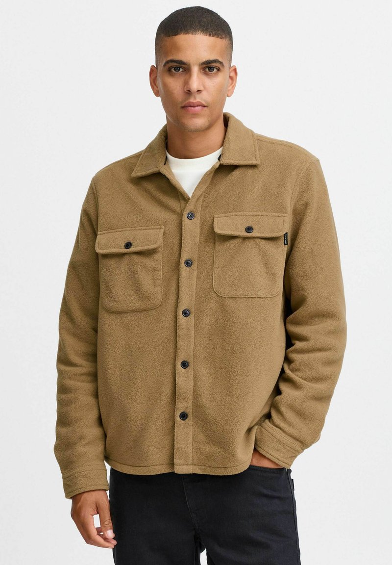 Bruine fleece shirtjack met een kraag, twee borstzakken en zwarte knopen. Zachte textuur en casual ontwerp, geschikt voor lagen.
