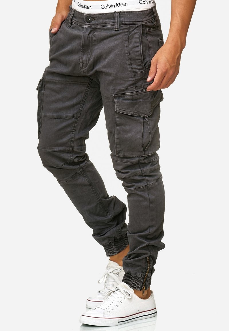 Gray cargo pants with elastic cuffs, multiple pockets, and a zipper detail at the ankles. Made from a sturdy material with a slightly textured finish.