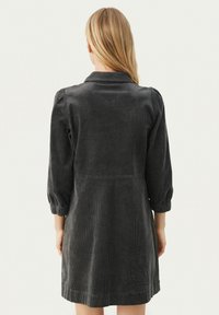 Dunkelgraues Cordkleid mit klassischem Kragen, drei Viertel Puffärmeln und taillierter Passform, ausgestattet mit vertikal gerippter Textur.