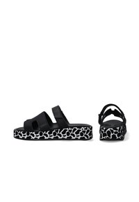 Černé sandály s dvěma širokými pásky a platformou, která má vzor černobílé zvířecí tisky. Hladký povrch a otevřený design vzadu.