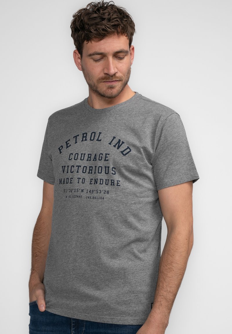 Camiseta de algodón gris con cuello redondo, mangas cortas y estampado frontal en azul marino que presenta texto y coordenadas para un toque adicional.