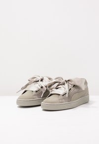 Zapatillas de ante gris con un diseño texturizado, que presentan cintas de satén como cordones y una suela de goma. Estilo minimalista y color versátil.