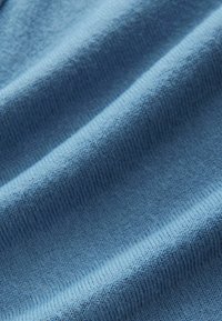 Jasnoniebieska tkanina o delikatnej teksturze, z jednolitym wzorem dzianiny i subtelnymi różnicami w odcieniu na całej powierzchni.