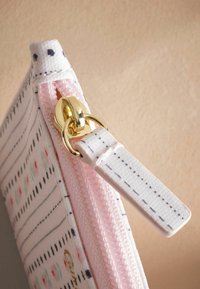 Roze etui met rits en een gestructureerd oppervlak, voorzien van zwarte en groene strepen, bloemaccenten en een gouden ritstrekkertje met een lus.